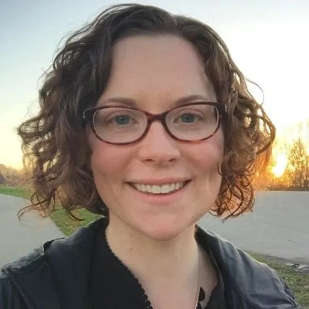 Portrait photo of smiling woman with short curly hair wearing glasses