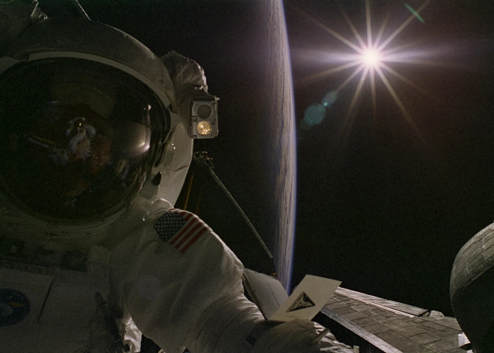 Astronaut on spacewalk with earth and sun visible in background