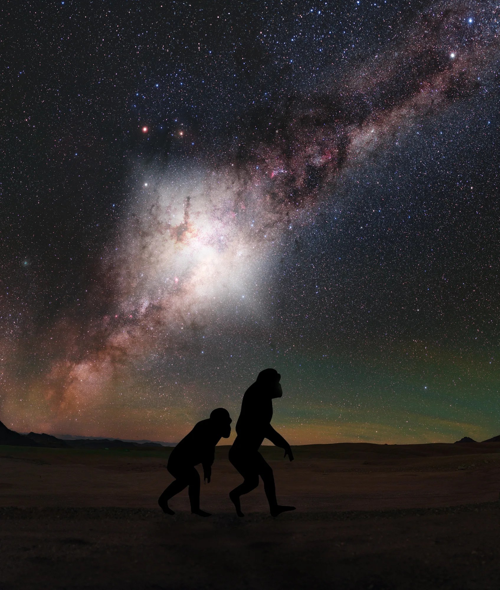 silhouette of primitive hominids with a brightly glowing Milky Way in the night sky