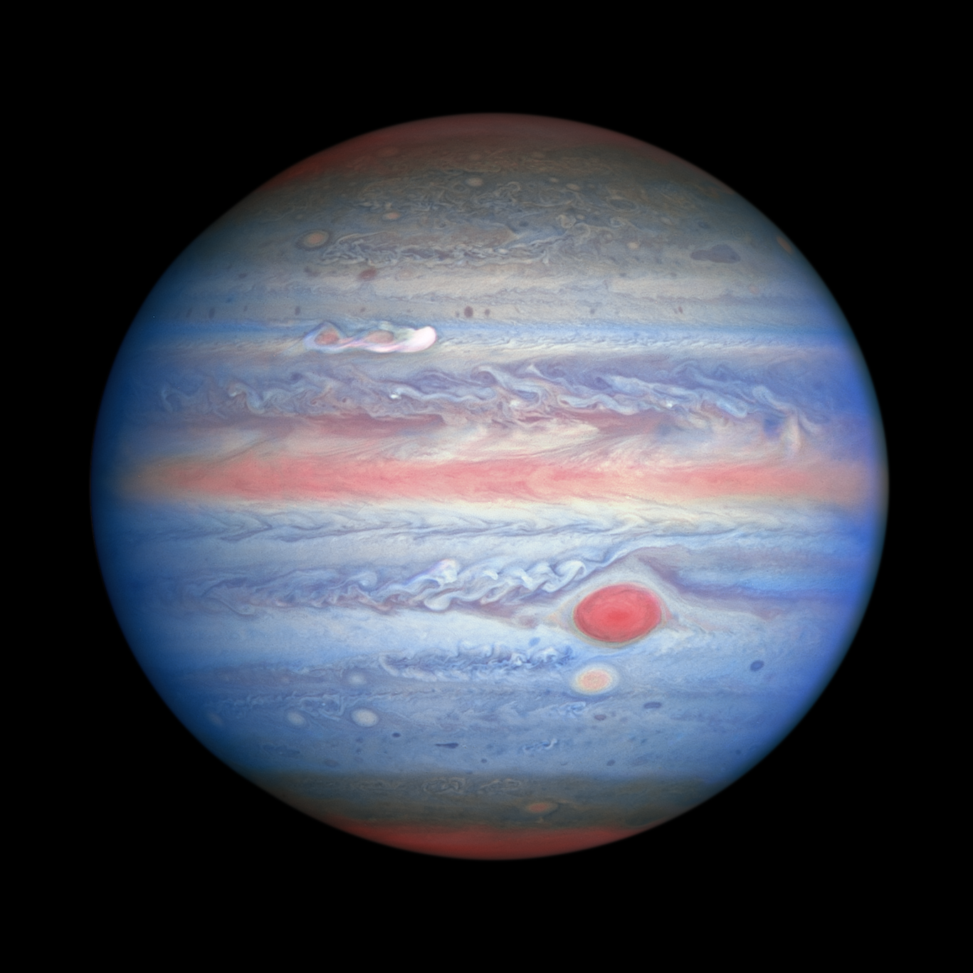 banded, red-white-and-blue-hued view of Jupiter in ultraviolet/visible/near-infrared light, as observed by Hubble