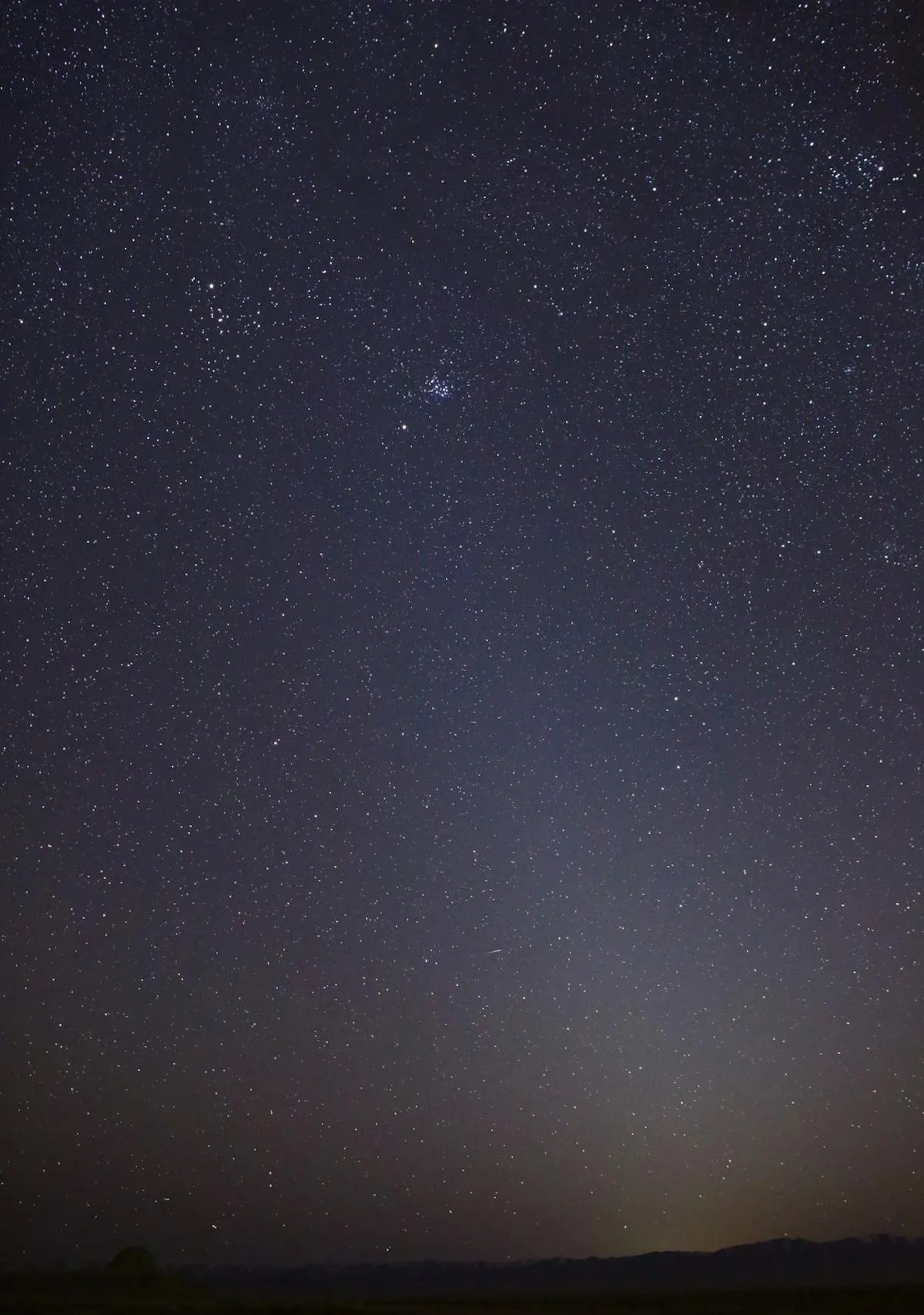 The night sky with a faint band of light that extends from the lower right to the upper left. A slight orange glow is visible along the horizon.
