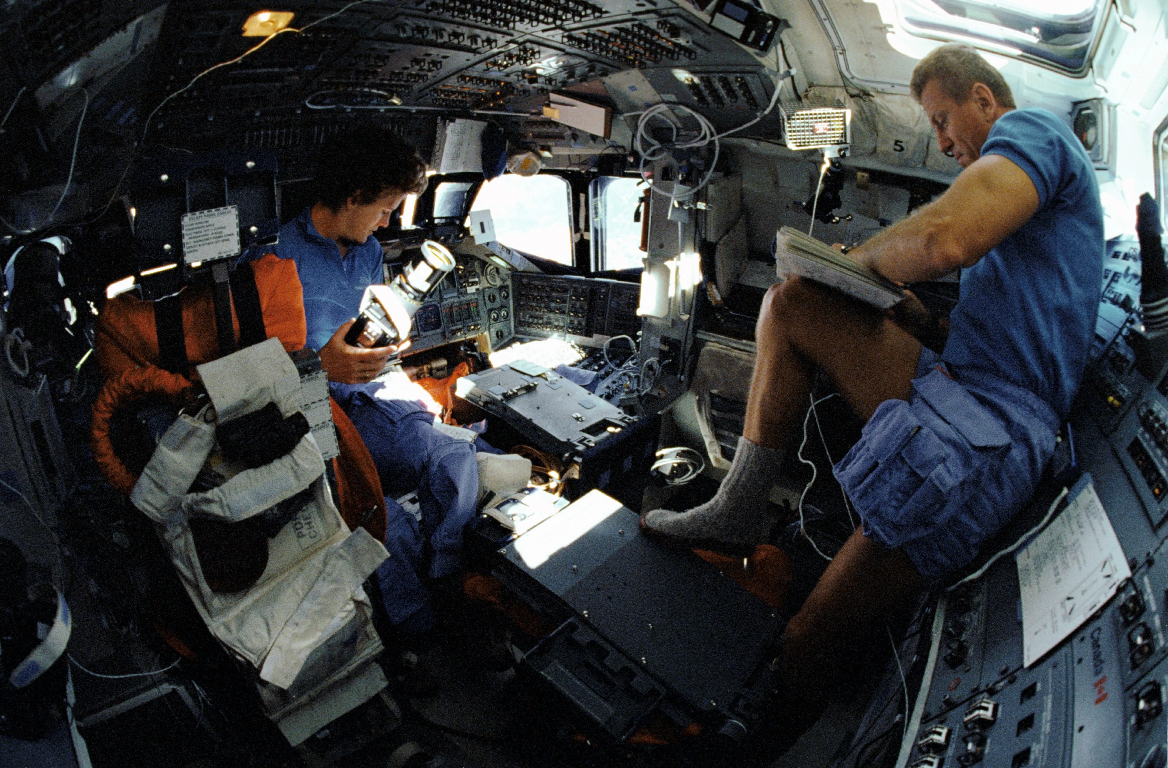 Astronauts float inside the pressurized flight deck of the Shuttle