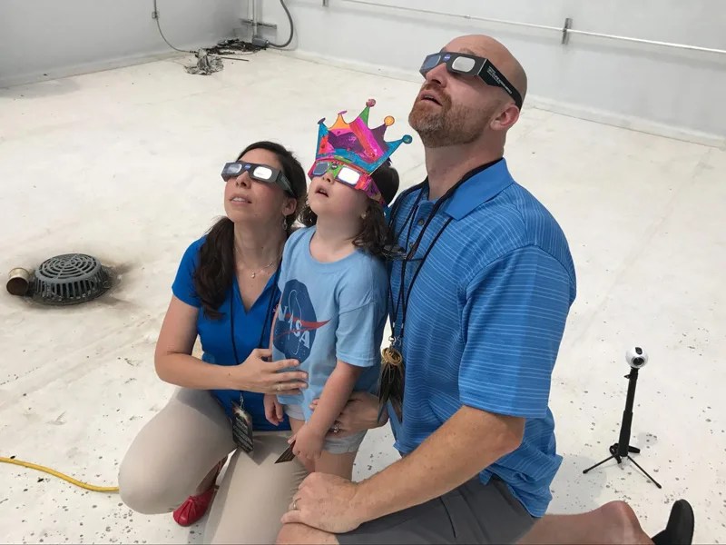 A family wearing eclipse glasses watches the total solar eclipse
