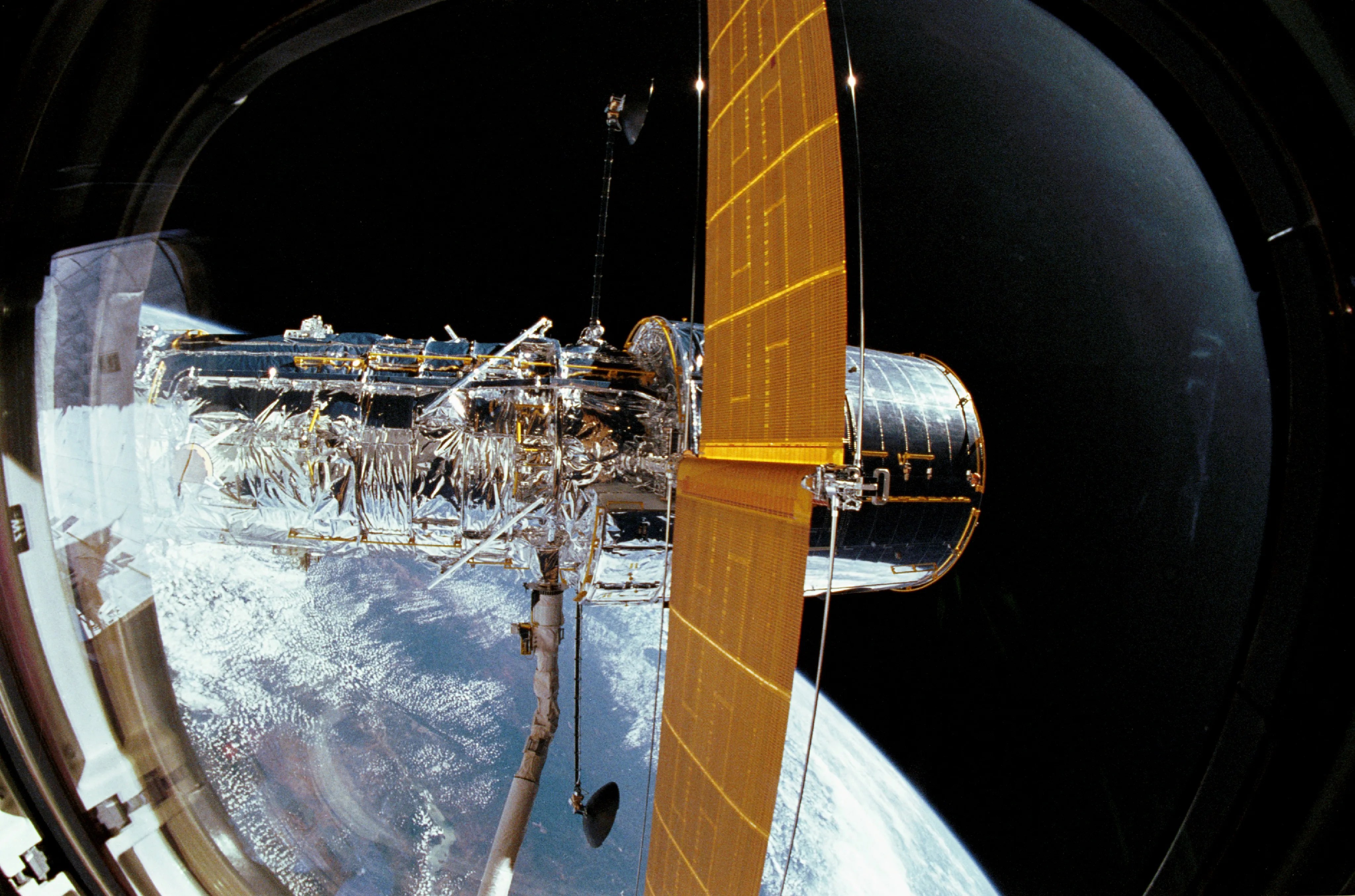 Da Hubble Telescope up in space gripped by tha space shuttle's robotic arm.
