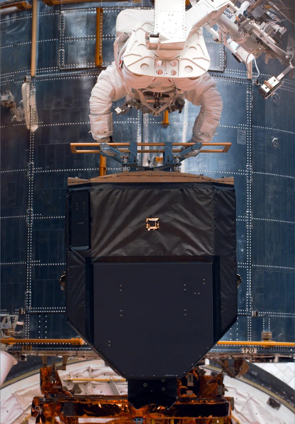 Astronauts holding equipment with Hubble behind them in space.