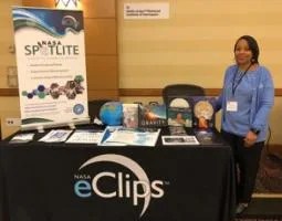 Joan Harper-Neely poses with the NASA eClips Spotlites exhibit table.