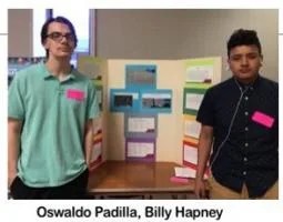 Two high schoolers pose in front of their project.