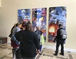 A handful of people look at an NIA collage on the wall.