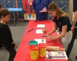 A young woman builds planets with Play-Doh for a boy.