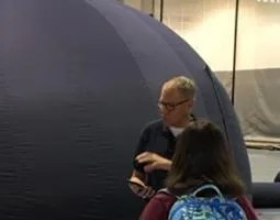 Dr. Michael Evans speaks to a student in front of a planetarium