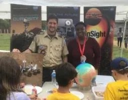 A man and woman present a Mission to Mars booth to cub scouts