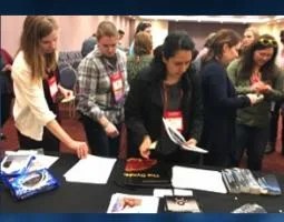 Female attendees take educational materials at the NASA exhibit booth