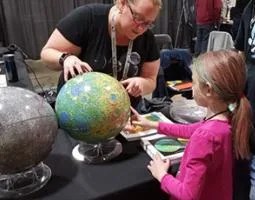 A woman and girl examine a globe.
