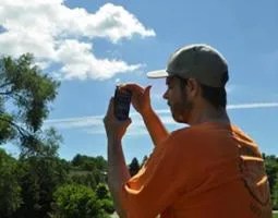 A man uses a smartphone to do cloud observations
