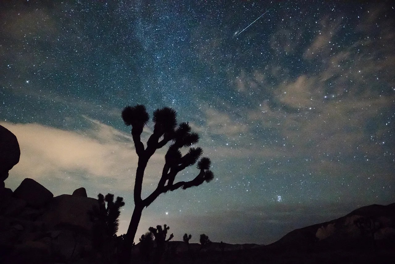 Meteor streaks over desert landscape.