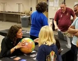 A woman holds a globe in front of children.