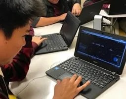 Students learning on black laptops