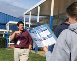 A young woman looks at a GLOBE Cloud Chart in front of a young man wearing a lanyard