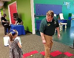 A little girl holds a dry-erase board next to a man in a green polo.