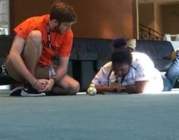 Two students on the floor with a BB-8 robot.