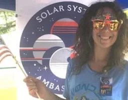 A woman wearing Wonder Woman sunglasses stands in front of an SSA display