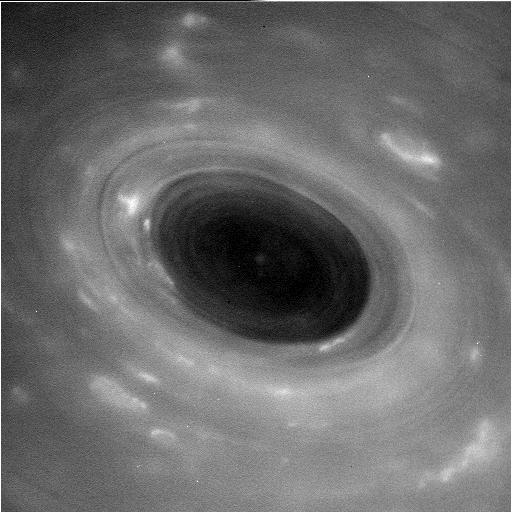 Black and white image of swirling storm on Saturn.