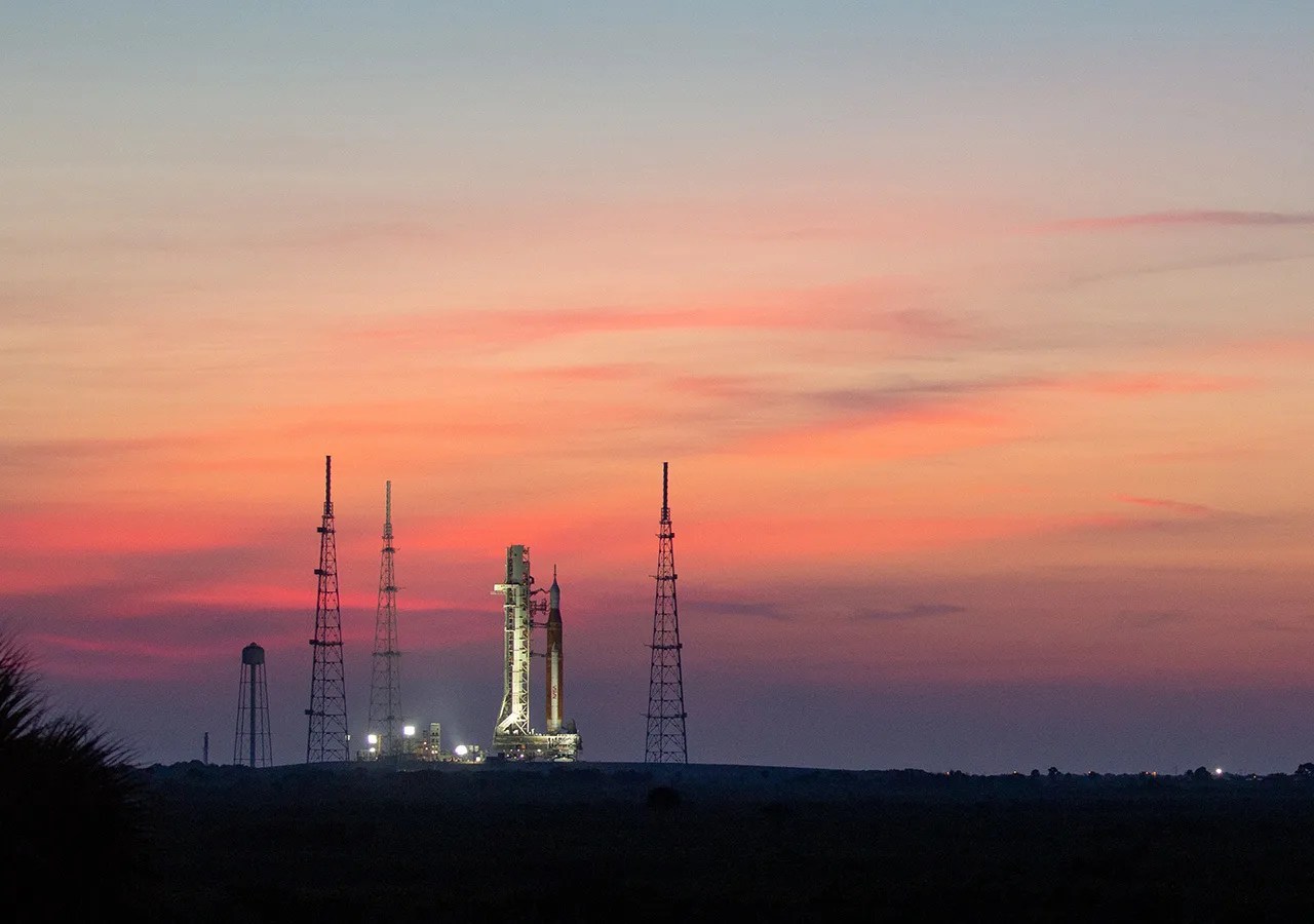 NASA's Space Launch System and Orion spacecraft roll to the launch pad at sunrise.
