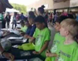 Children in lime green t-shirts at display tables.