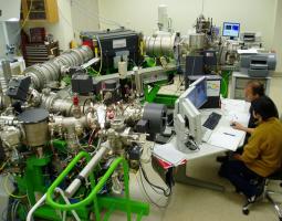 This image shows the Cameca ims 1280 equipped with a Hyperion II ion source and SCAPS detector available at the University of Hawai’i. Two individuals are pictured utilizing the instrument.