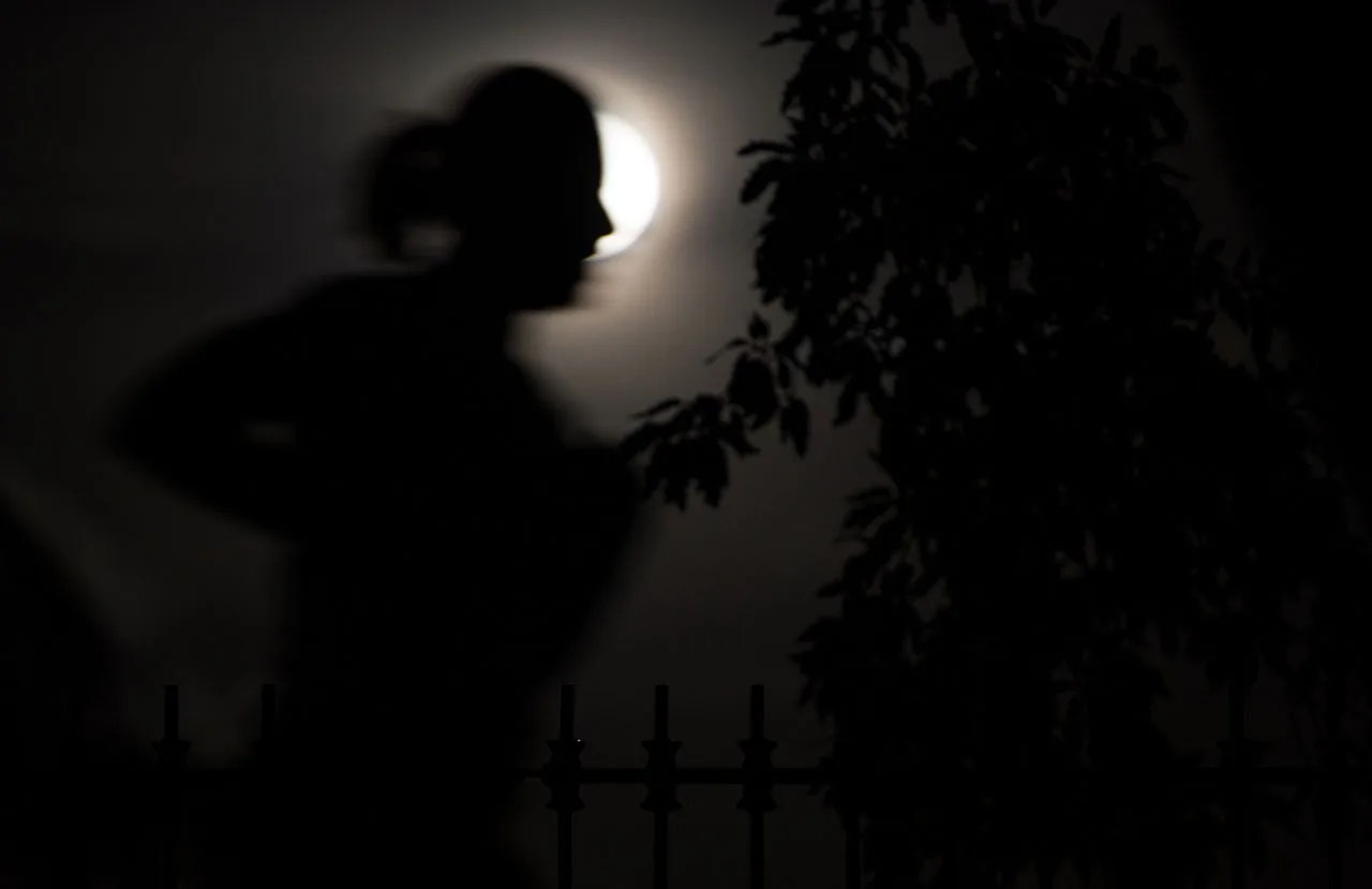 Jogger silhouetted in front of a full Moon.