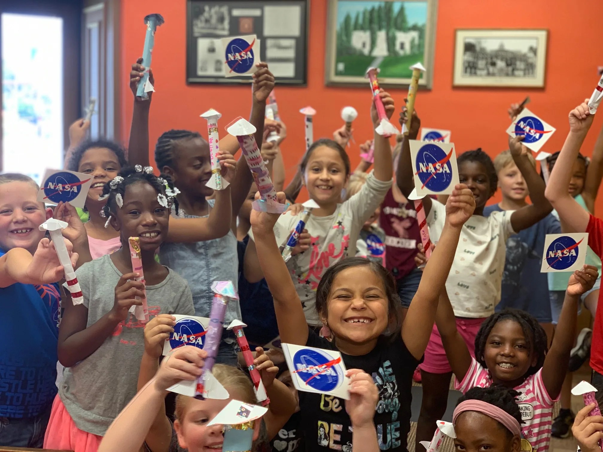 Children showing off their paper rockets and NASA stickers.