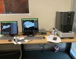 This image shows the benchtop scanning electron microscope (SEM) (a Phenom XL from Nanoscience instruments) at the Lunar and Planetary Institute as well as two computers displaying SEM data on a sample.