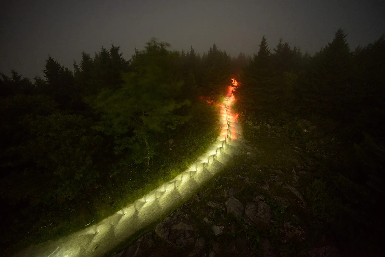 Light trail made by hikers going up a mountain in the dark.