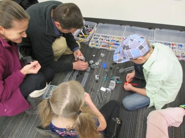 Photo of four children sitting on the floor and working together on a science project.