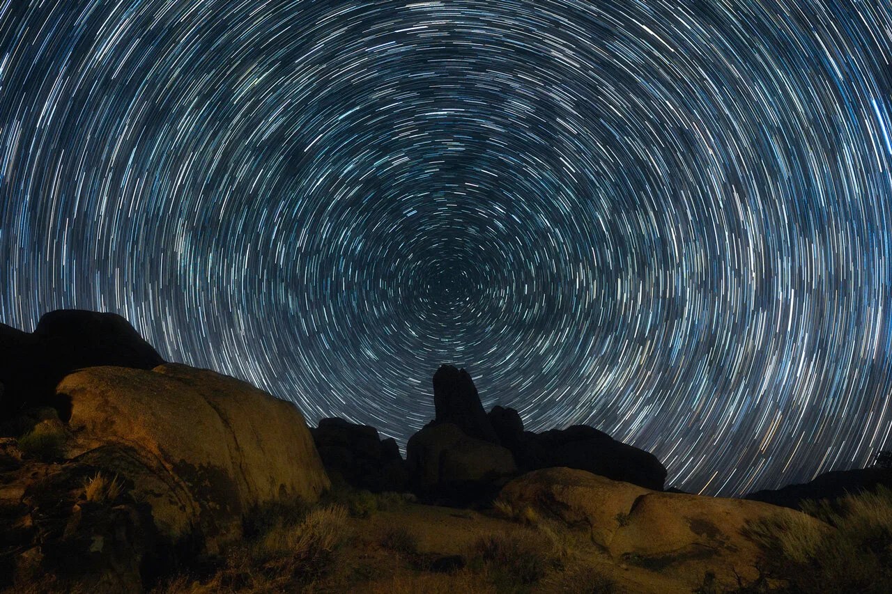 夜间恒星的长曝光图像，捕捉它们围绕北极星的圆周运动