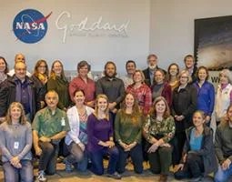 Group photo in front of wall with NASA Goddard signage