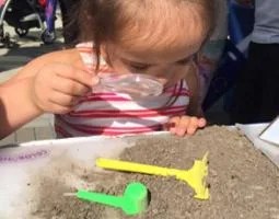 A little girl looks at soil through a magnifying glass
