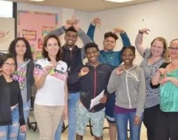Students and teachers pose using sign language.