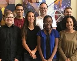 Students and staff pose in front of mounted canvas prints