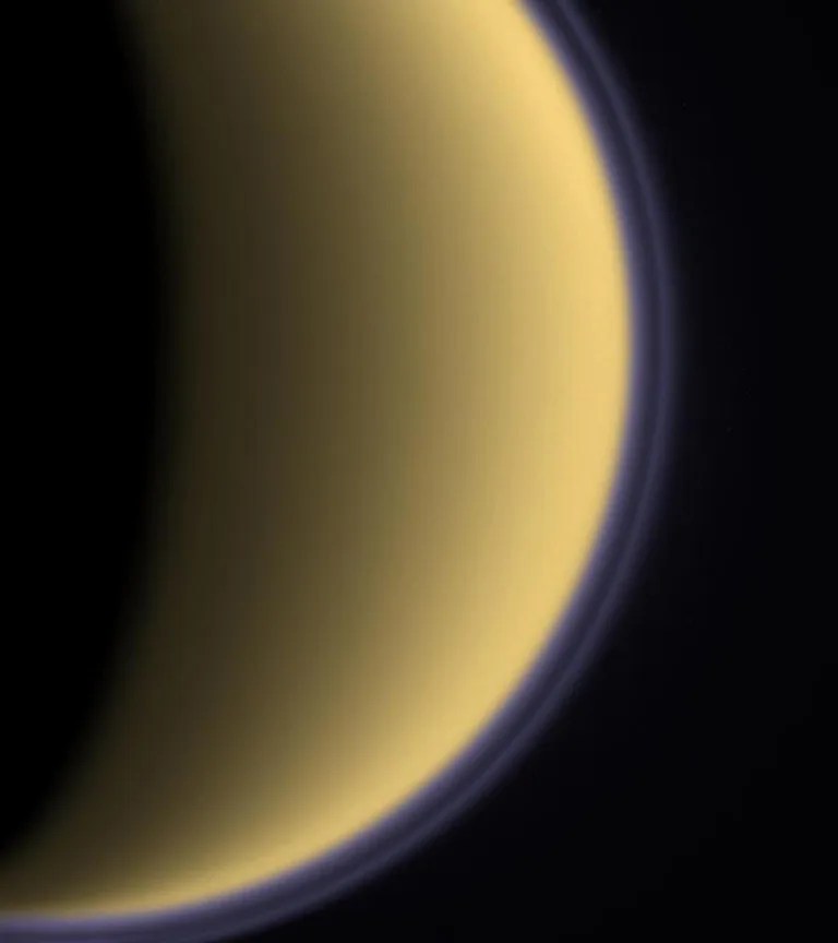 Encircled in purple stratospheric haze, Titan appears as a softly glowing sphere in this colorized image taken one day after Cassini's first flyby of the moon on July 2, 2004.