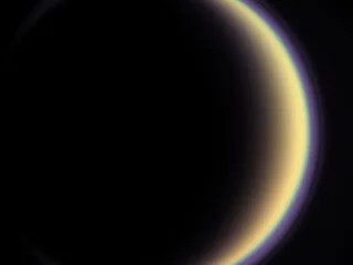 Titan's Halo: With its thick, distended atmosphere, Titan's orange globe shines softly, encircled by a thin halo of purple light-scattering haze.