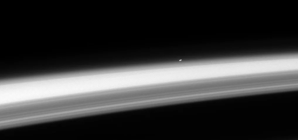 The trinary star Alpha Centauri, hangs above the horizon of Saturn
