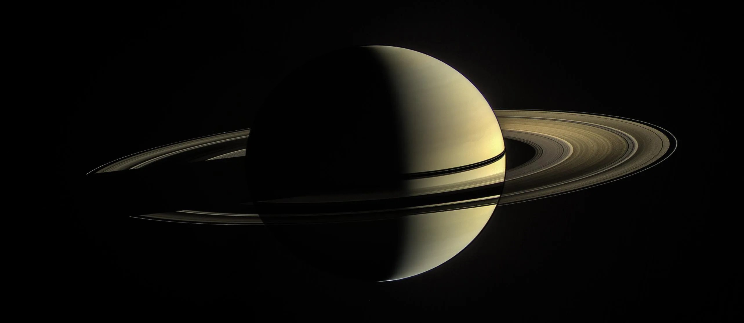 Full view of Saturn partially illuminated by the Sun.