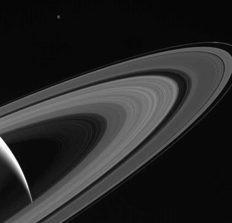 Cassini gazes across the icy rings of Saturn toward the icy moon Tethys, whose night side is illuminated by Saturnshine, or sunlight reflected by the planet. › Full image and caption
