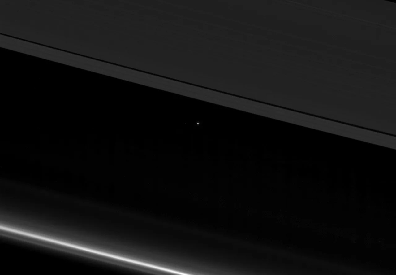 A view of planet Earth as a point of light between the icy rings of Saturn
