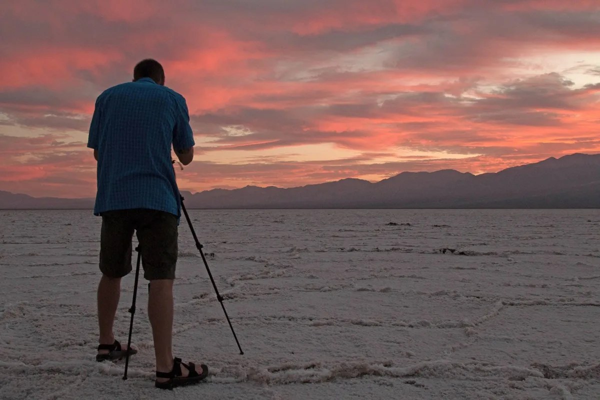 Photographer in desert at sunset.