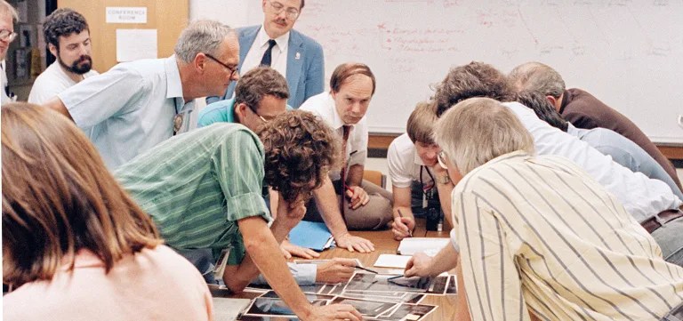 Members of the Voyager science team pore over fresh images of Neptune's moon Triton as data from Voyager 2 stream into JPL in August 1989. Image Credit: NASA/JPL-Caltech