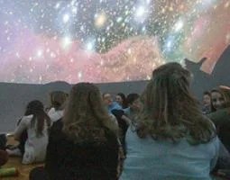 Middle school students sit in a planetarium
