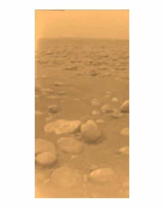 Small pebbles stretch off into the distance of the orangish surface of Titan.