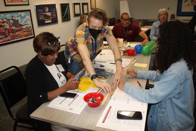Photo of workshop participants working together to model the distances of the planets on a strip of paper.